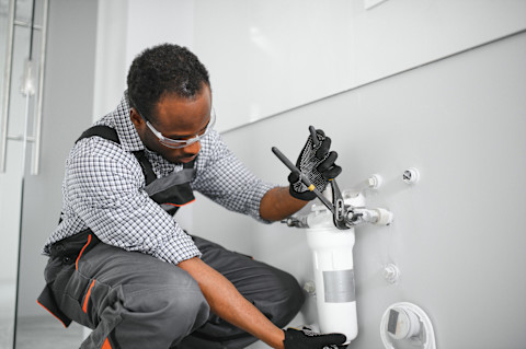 This image shows a plumber installing a water softener as part of a plumbing project.