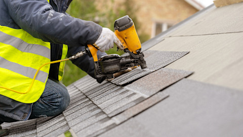 This image shows a roofer installing roofing materials on a roof.