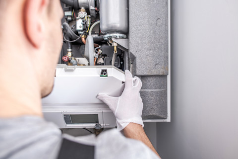 Closeup of a technician working on a central heating furnace unit.