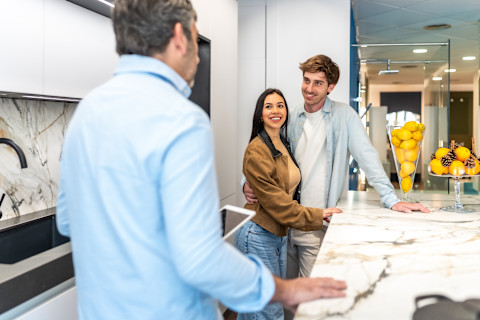 Two people are looking happy at their new kitchen plans.