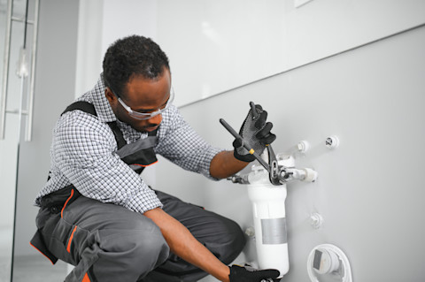 This image shows a plumber installing a water softener as part of a plumbing project.